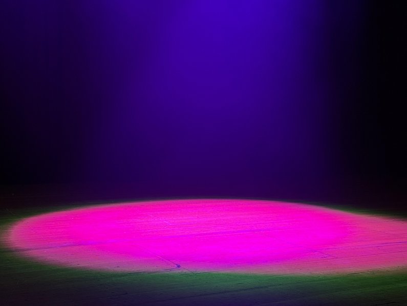 pinkfarbener Lichtspot auf Bühnenboden