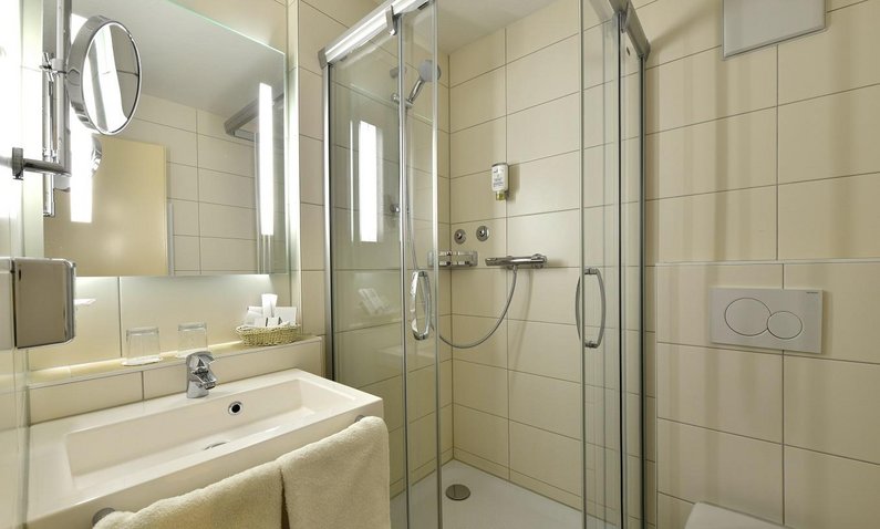 weißes Hotelbad mit Dusche, Spiegel und Waschbecken