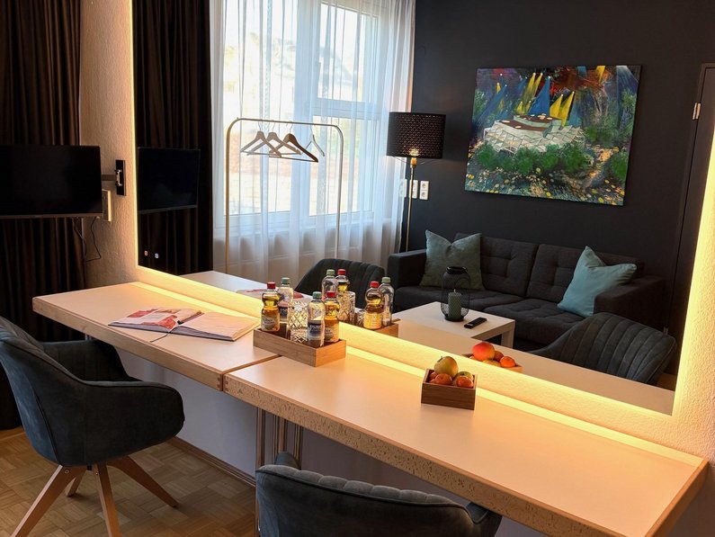 Künstlergarderobe, Sofa, Tisch, bequeme Stühle, Stehlampe, Bild an der Wand, Teppich unter dem Couchtisch, Wohnzimmergefüh
